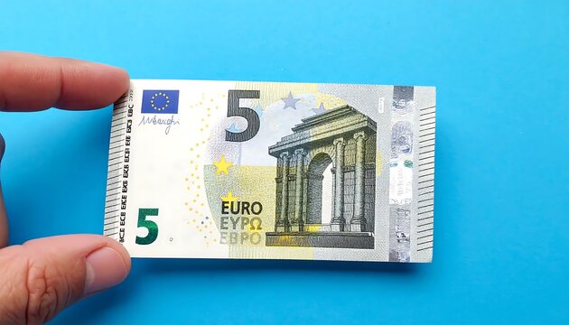 A hand holds a 5 Euro banknote against blue background