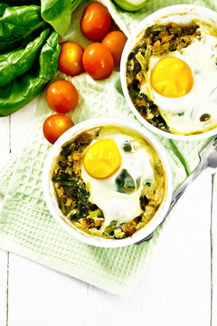 Scrambled eggs with spinach in bowl on light board top