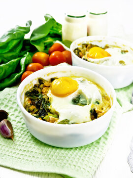 Scrambled eggs with spinach in bowl on white wooden board