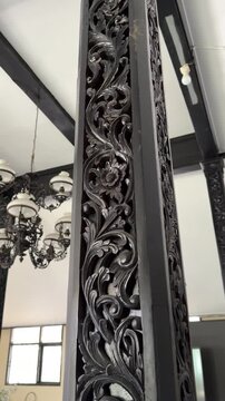 Ornate Vintage Chandelier Hanging from a White Ceiling with Carved  Dark Wooden Beams