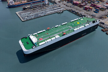 Obraz premium Aerial view of a huge Ro-Ro vehicle transport ship in the process of unloading on maritime port platforms