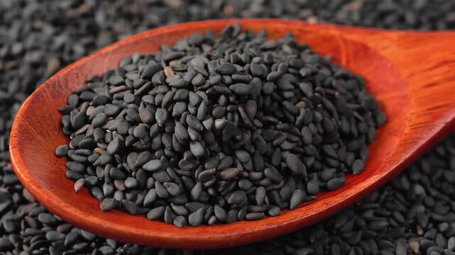 A wooden scoop filled with tiny, aromatic black sesame seeds