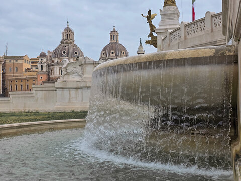 Close-up of the fountain at Altare della Patria with Santa Maria di Loreto and Santissimo Nome di Maria al Foro Traiano churches in the background.
