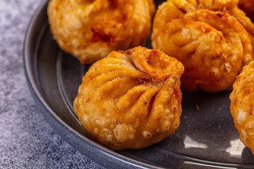 Golden fried dumplings momo in a skillet with fresh vegetables and flatbread