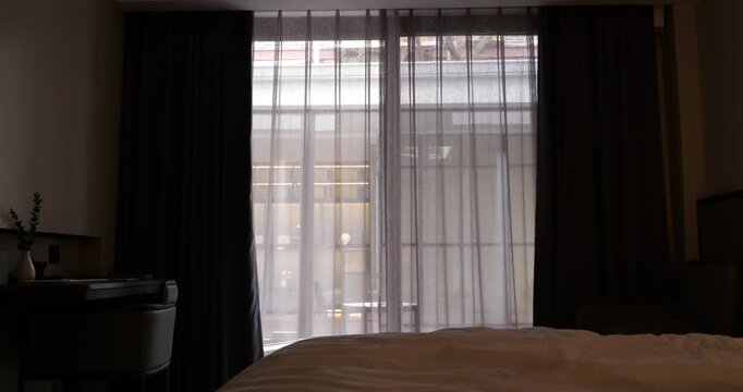 Modern bedroom with automatic curtains, opening to reveal large window overlooking inner yard, visible through semi-transparent veils. Soft light and welcoming atmosphere perfect for starting new day