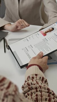 Vertical over the shoulder shot of anonymous female hiring manager handing resume to unknown applicant because finding it insufficient