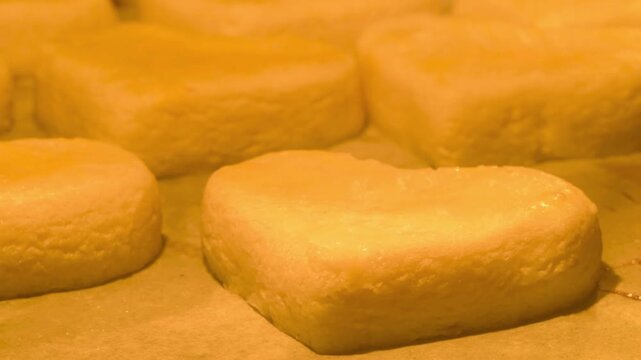 Golden heart-shaped biscuits are baking in a hot oven, capturing the cozy process of home baking.