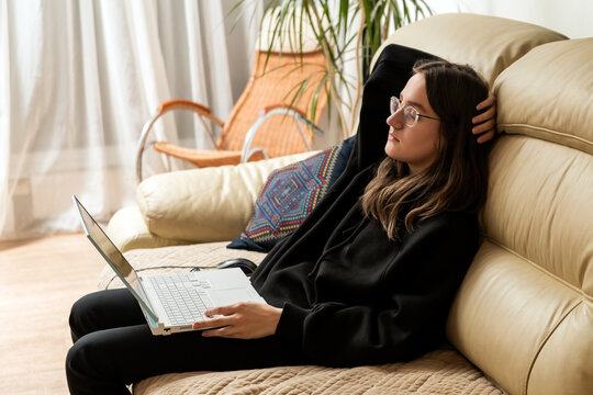 Woman resting on couch with laptop, taking break from remote work