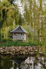 Duck house on small island under willow tree in park pond