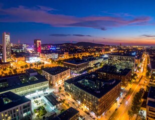 Obraz premium Aerial cityscape at dusk with illuminated buildings and streets