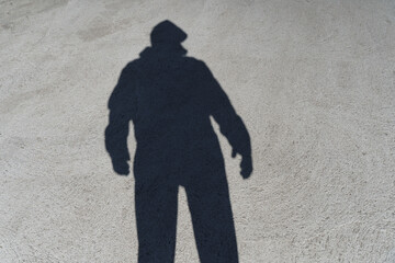 Fototapeta premium Dark shadow of a lonely person on the ground in the street. Stranger. Anxiety, depression, loneliness, fear concept. 