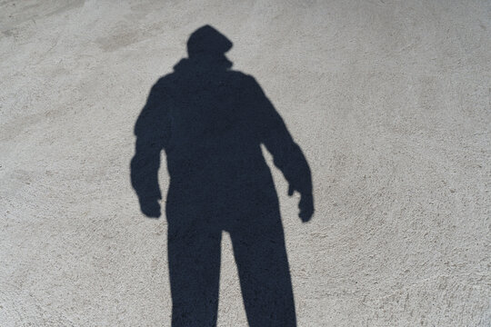 Dark shadow of a lonely person on the ground in the street. Stranger. Anxiety, depression, loneliness, fear concept. 