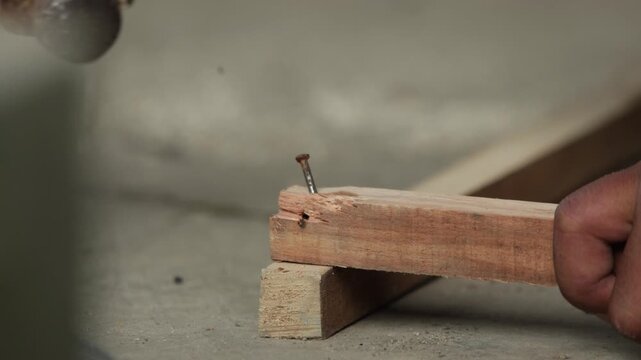 Close Up Hammering Nail Into Wooden Board. Carpenter Hammering Nail Into Wood Close Up