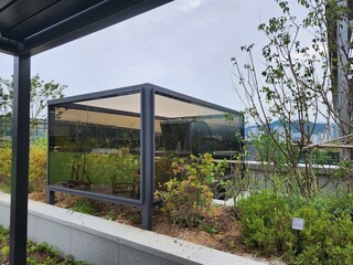 Fototapeta premium Contemporary glass smoking booth installed in rooftop garden of office building