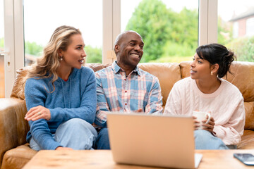 Three friends sit on a sofa in a living room