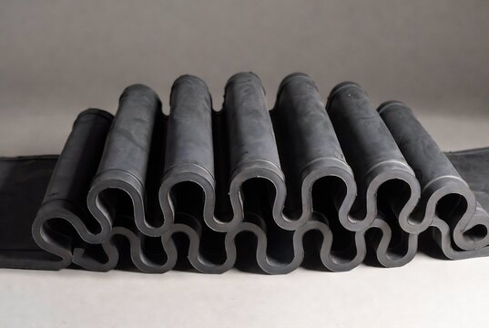 Rubber conveyor belts are arranged in a row on a white surface.