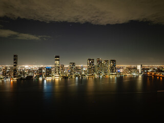 Fototapeta premium Miami downtown skyline at night reflected in Biscayne Bay, aerial cityscape