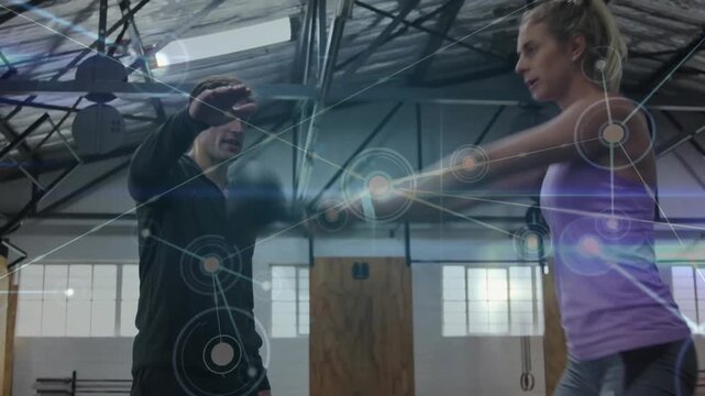 Coach reaching, cueing client swinging kettlebell fixing form while fitness overlay tracing swing