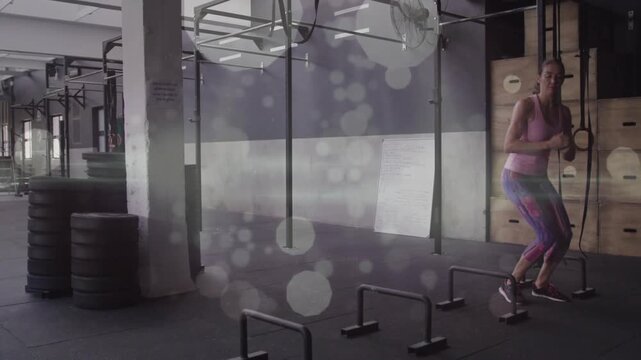 Woman shifting squat weight, initiating lateral hops over parallettes, training fitness agility