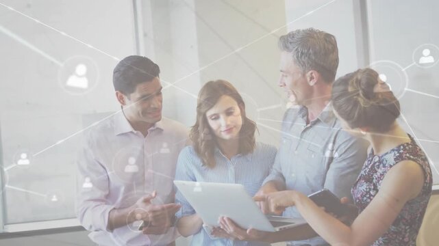 Team of four leaning over laptop man pointing initiating network overlay aligning business plans