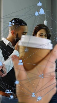 Vertical video: Business team scanning docs and phone, hand lifting cup drawing focus amid AR icons