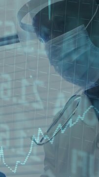 Vertical video: Clinician wearing shield and mask tracking rising data with dotted chart animating