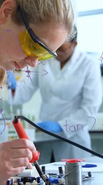 Bringing iron tip, woman lab coat goggles soldering board joining components at bench, copy space