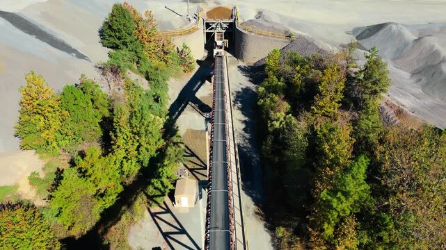 Drone flyover along conveyor belt leading to aggregate hopper filling freight train