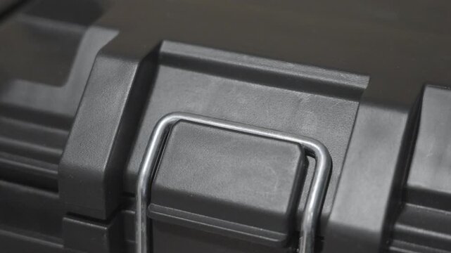 A large hinge in the locked position on a large plastic tool bin.