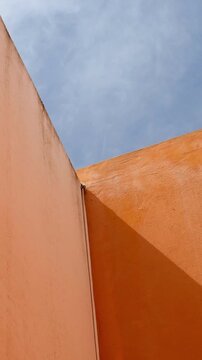 Low-angle view of a partially cloudy sky and colorful walls describing a geometric pattern.