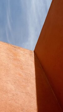 Low-angle view of a partially cloudy sky and colorful walls describing a geometric pattern.