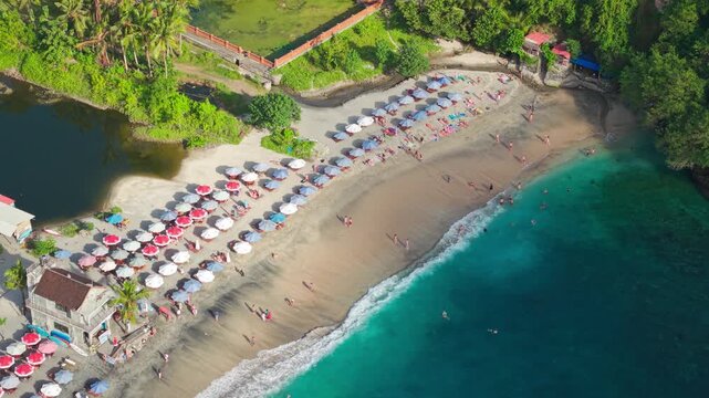 Orbiting drone view of Crystal Bay, Nusa Penida, showing beach, parasols, and clear water