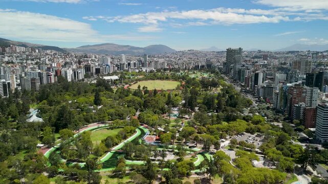 Aerial parallax over Parque La Carolina vast green urban park surrounded by Quito modern high-rise skyline and Andean mountains