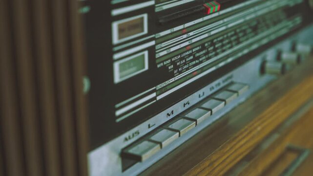 Close-up of hand operating push switches on vintage radiogram radio player. Suitable for retro electronics, broadcasting equipment and audio technology visuals.