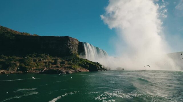 Niagara Falls waterfall with rising mist plume and flying seagulls above turquoise river water