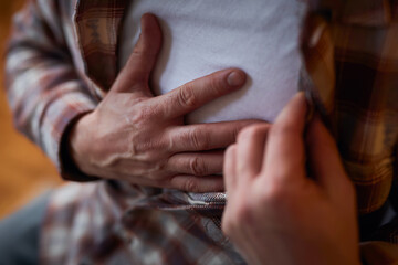 Man with heart problems, chest and abdominal pain at home measuring and checking pulse.