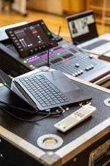 Laptop connected to a digital audio mixing console in a sound control room. Audio engineering setup with faders, screens, and remote control on a workstation, shallow depth of field