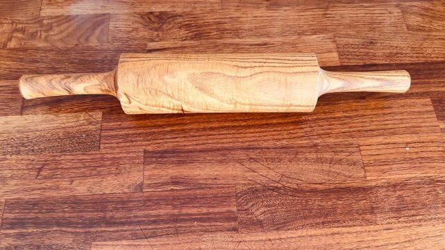 Luxury handmade rolling pin made of premium walnut wood on an oak panel. Professional kitchen tool for dough. High-end wooden kitchenware with natural grain texture, minimalist background.