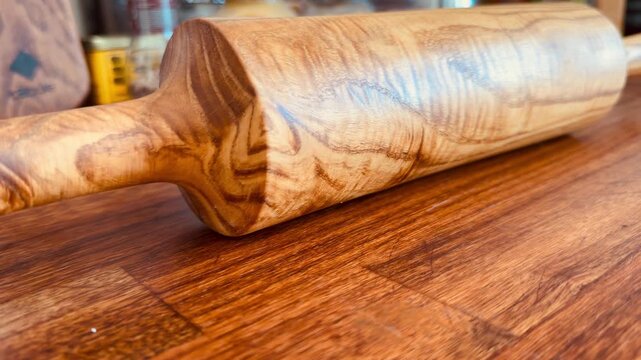 Luxury handmade rolling pin made of premium walnut wood on an oak panel. Professional kitchen tool for dough. High-end wooden kitchenware with natural grain texture, minimalist background.