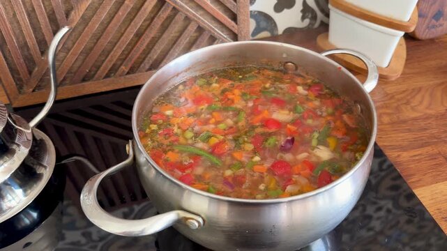 Traditional vegetable soup Chorba in a pot on a luxury kitchen with oriental tile. Healthy Halal meal for Ramadan Iftar. Authentic Asian cuisine cooking process in a stylish home interior.