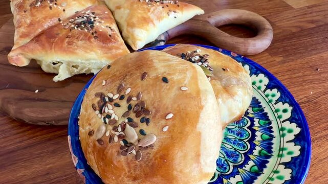 Assorted meat samsa for Ramadan Iftar on a traditional ceramic plate and ash wood board. Freshly baked puff pastry with various seeds. Delicious Halal food for breaking the fast, Ramadan Kareem.