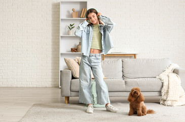 Teenage girl in headphones with cute Toy Poodle dog listening to music at home