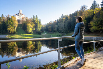 Fototapeta premium Girl enjoys аmazing autumn view of old castle and lake of Trakoscan in Zagorje, northern Croatia.