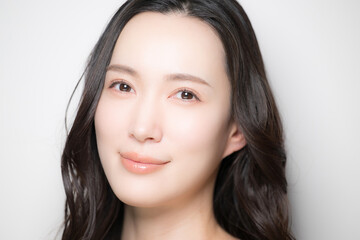 Obraz premium 黒髪が綺麗で白背景の若い女性のビューティーイメージ スキンケアなどの肌が気になるイメージ のカメラ目線