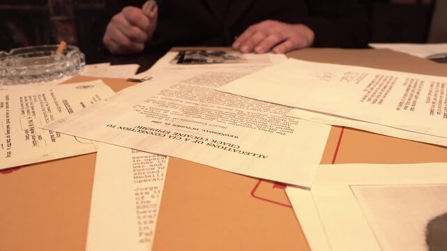 Detective Looking at Investigation and Top Secret Files and Document at Office Desk, Close Up