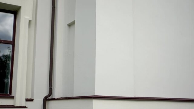 Wall pipe the facade of the modern building with a vertical drain pipe and window