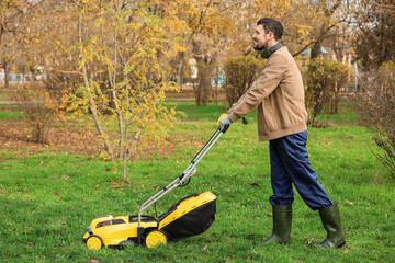 Male gardener using lawn mower outdoors