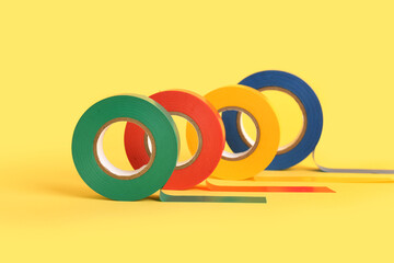 Different insulating tape rolls on yellow background, closeup