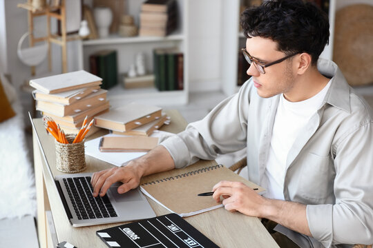 Male screenwriter with laptop writing script at table in office