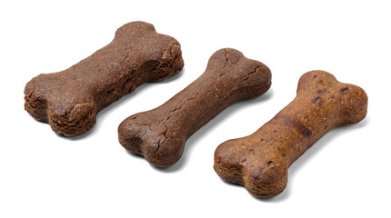 three delicious bone-shaped dog biscuits, showcasing a variety of rustic brown tones and distinct textures, are set against a stark transparent background for a dramatic presentation.